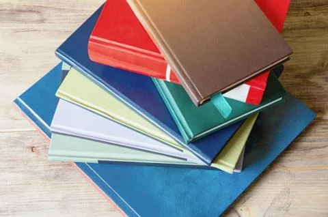 Stack of books of different sizes and colors on the table Stock Photos