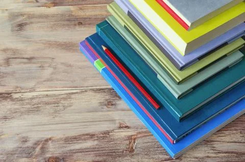 Stack of books of different sizes and colors on rustic background Stock Photos