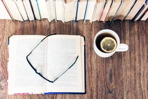 Stack of books education background, open book, glasses, and cup of tea with  Stock Photos
