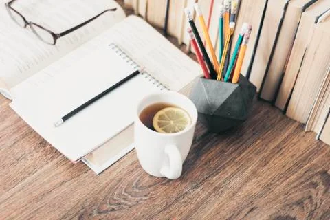 Stack of books education background, open notebook, glasses, and cup of tea w Stock Photos