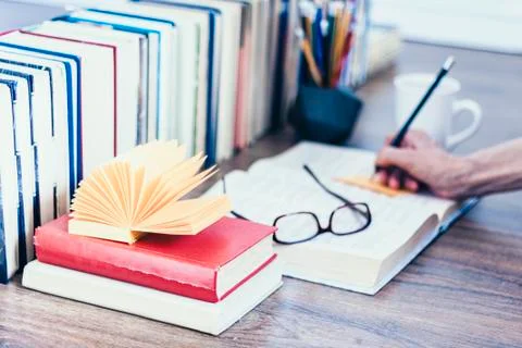 Stack of books education background, open book, female hand with pencil, glas Stock Photos
