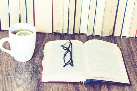 Stack of books education background, open book, glasses, and cup of tea with  Stock Photos