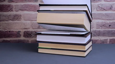 Stack of books falling on gray table for study and learning Stock Footage 310604594