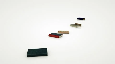 The stack of books falls and the books are scattered on the white, shiny surface Stock Footage 155179241