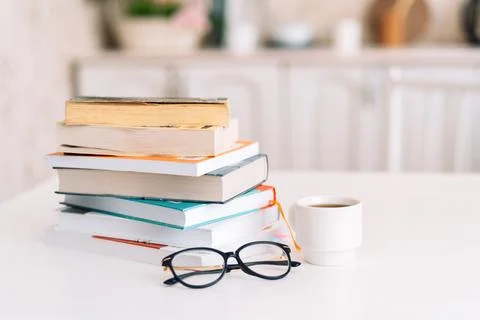 Stack of books with glasses and cup of coffee standing on table Stock Photos
