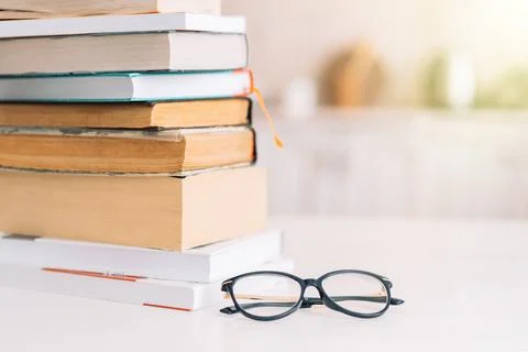 Stack of books with glasses standing on table in front of the room Stock Photos