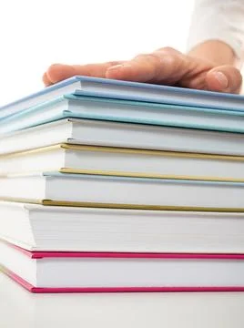 Stack of books with hand on top of it Stock Photos