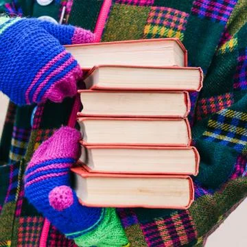 A stack of books in the hands of a man in bright clothes. A man distributes b Foto stock