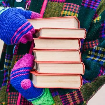 A stack of books in the hands of a man in bright clothes. A man distribute... 스톡 사진
