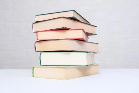 A stack of books lying on a white table, reading and education concept Stock Photos
