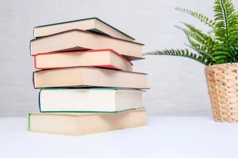 A stack of books lying on a white table, reading and education concept Stock Photos