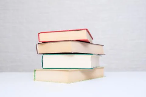 A stack of books lying on a white table, reading and education concept Stock Photos