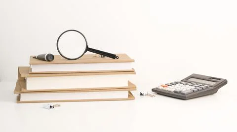 Stack of books with magnifier on top and calculator near. Back to school. Stock Photos
