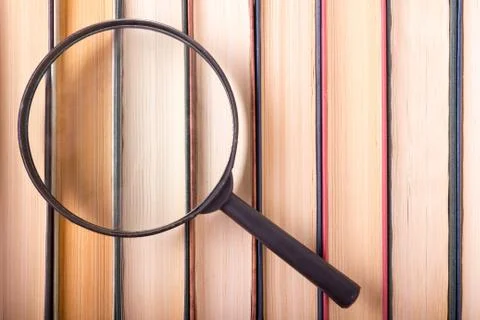 Stack of books with magnifying glass. Search information Stock-Fotos