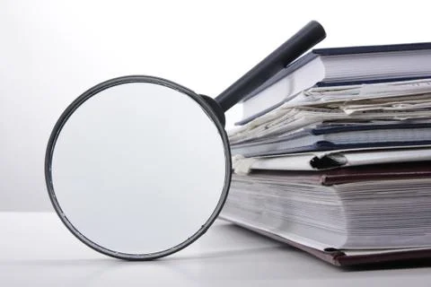 Stack of books with magnifying glass. Search information Stock Photos