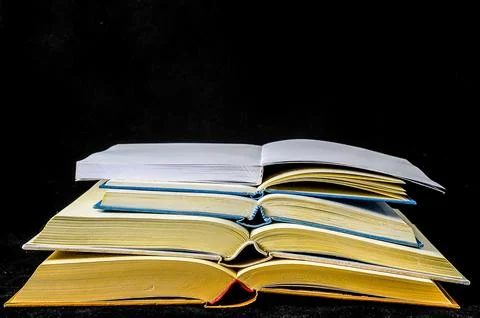 A stack of books with one open to the middle 写真素材