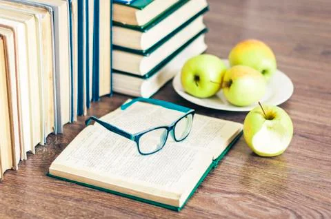 Stack of books, open book, glasses and green apples, background for education Stock Photos