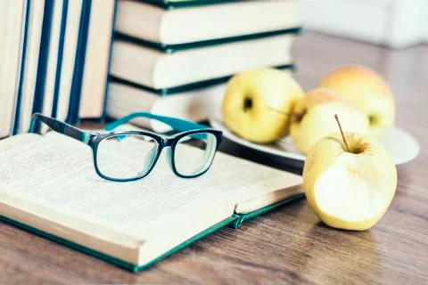 Stack of books, open book, glasses and green apples, background for education Stock Photos