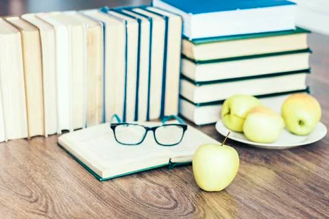 Stack of books, open book, glasses and green apples, background for education Stock Photos