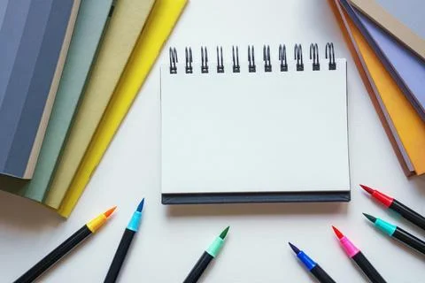 Stack of books, open spiral notepad and colored markers. Copy space Stock Photos