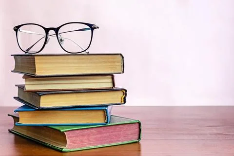 Stack of books with reading glasses on top Stock Photos
