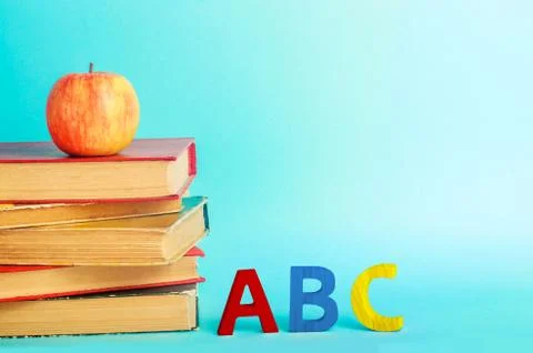 A stack of books with a red apple and letters of the ABC English alphabet sta 스톡 사진