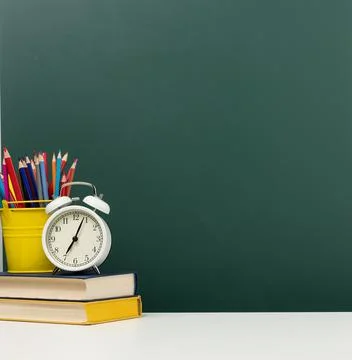 Stack of books, a round alarm clock and multicolored pencils on the backgroun Stock-Fotos