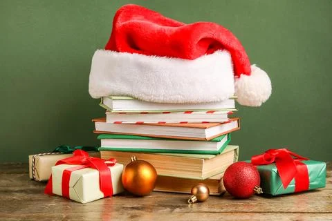 Stack of books with Santa hat, Christmas balls and gift boxes on wooden table Stock Photos