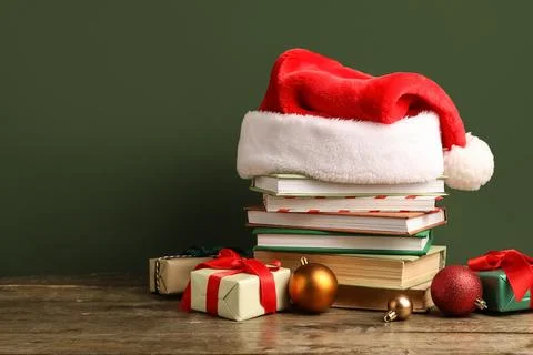 Stack of books with Santa hat, Christmas balls and gift boxes on wooden table Stock Photos