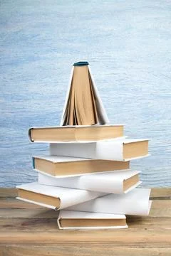 Stack of books in the shape of a Christmas tree on a blue background. Back to Stock Photos