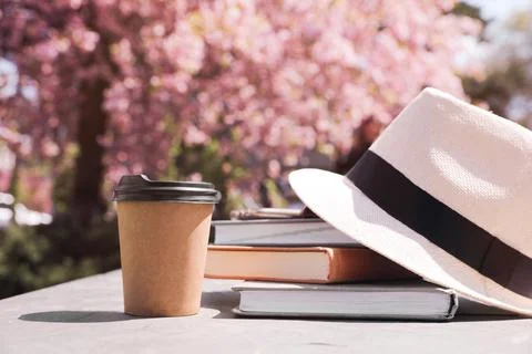 Stack of books, smartphone and hat on table in park Stock Photos