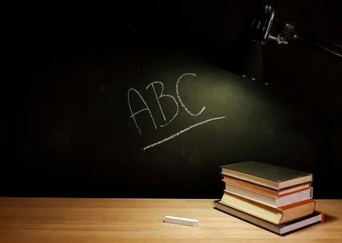 Stack of books on a table with ABC text on the blackboard 스톡 사진