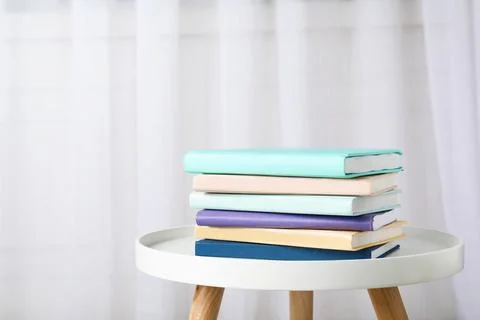 Stack of books on table against curtain. Space for text 스톡 사진