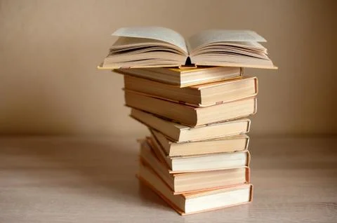 A stack of books is on the table and one book is open Stock Photos