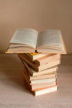 A stack of books is on the table and one book is open Stock Photos