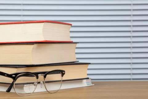 Stack of books on a table with eye glasses Stock Photos