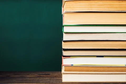 A stack of books on a table with a green background Stock Photos