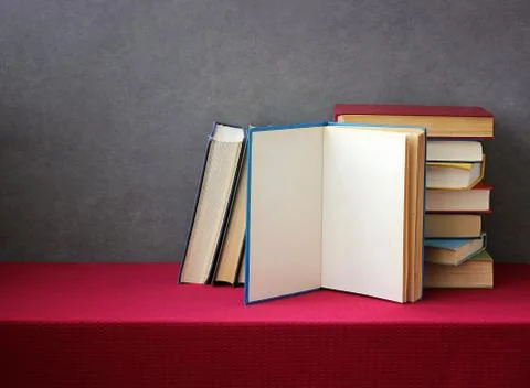 A stack of books on the table with a red tablecloth. Stock Photos