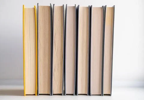 Stack of books on a white background. One book is yellow. Stock Photos