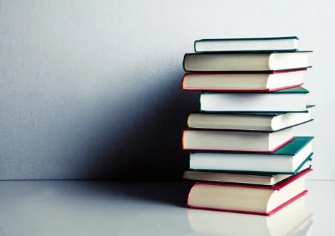 Stack of books on white reflective surface Foto stock
