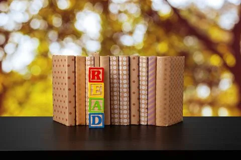 Stack of books on wooden table against blurred background Stock Photos