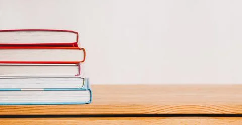 A stack of books on wooden table. Mock up with education and reading concept. Stock Photos