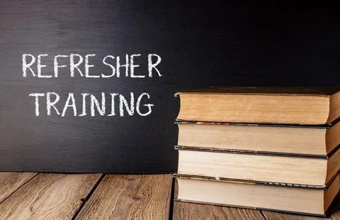 A stack of books with the word refresher training written on a chalkboard Stock Photos