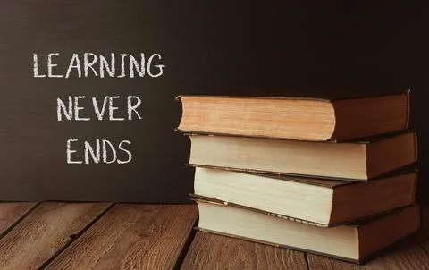A stack of books with the words learning never ends written on a chalkboard Stock Photos