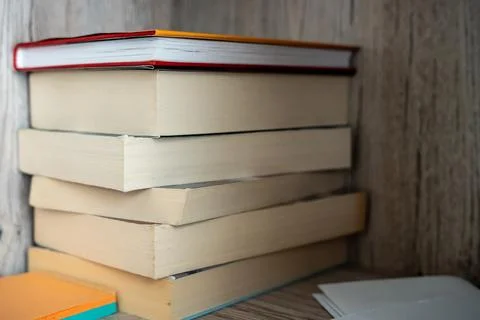 Stack of books with worn pages resting on a wooden surface in a home interior Stock Photos