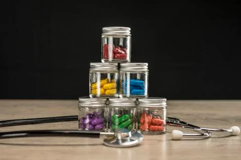 Stack of bottles filled with colored prescription pills Stock Photos