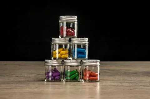 Stack of bottles filled with colored prescription pills Stock Photos