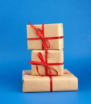 Stack of boxes wrapped in brown paper and tied with a red bow, gifts on a ... 写真素材
