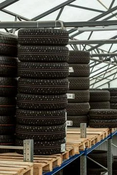 Stack of brand new studded winter car tires on wooden pallet inside logisti.. 스톡 사진