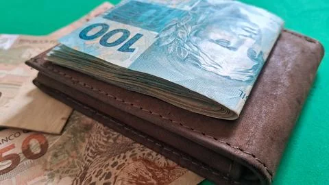 Stack of brazilian real banknotes resting on a brown leather wallet Stock Photos